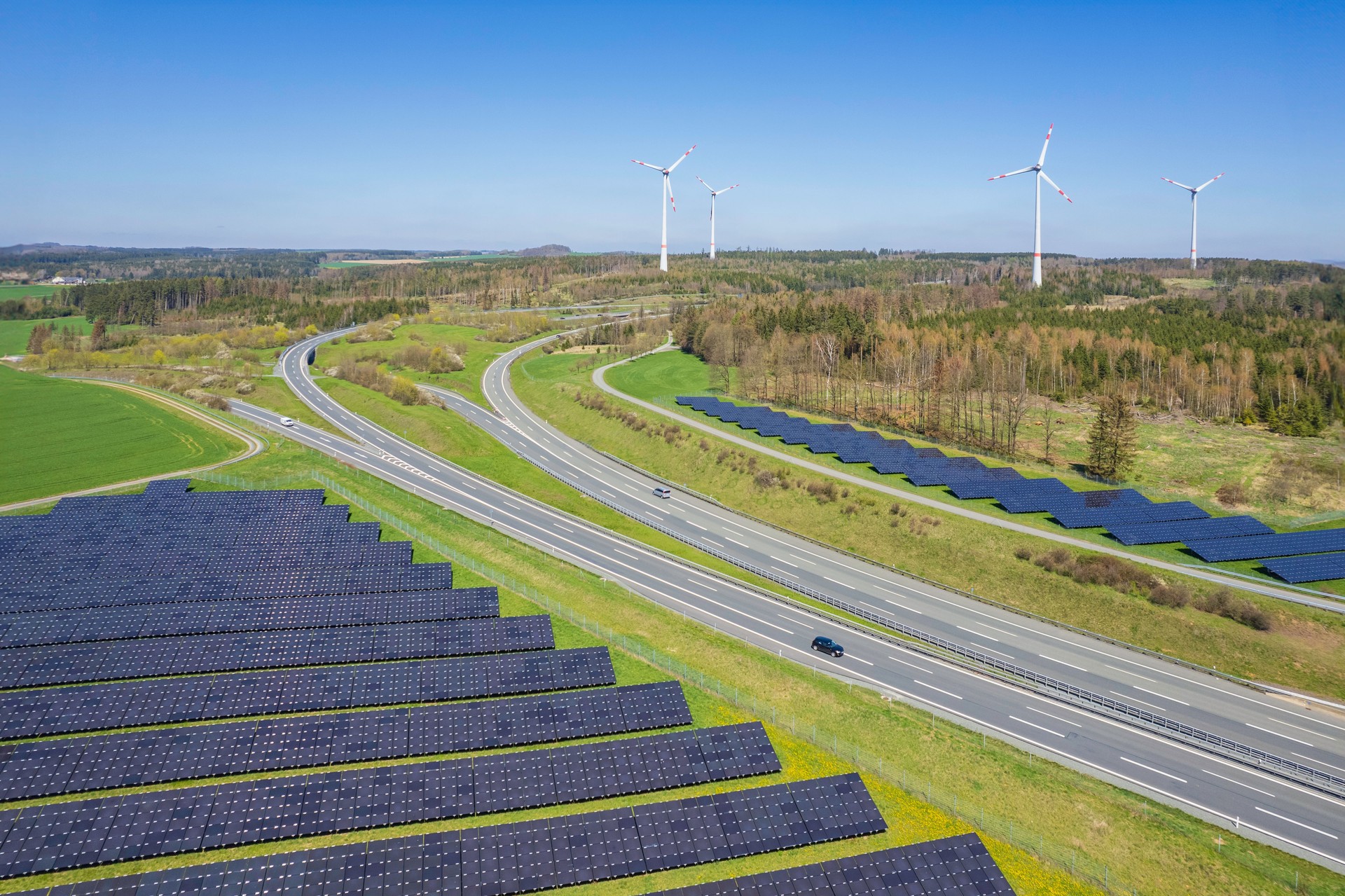 Vue aérienne des panneaux solaires modernes et des éoliennes près de l’autoroute